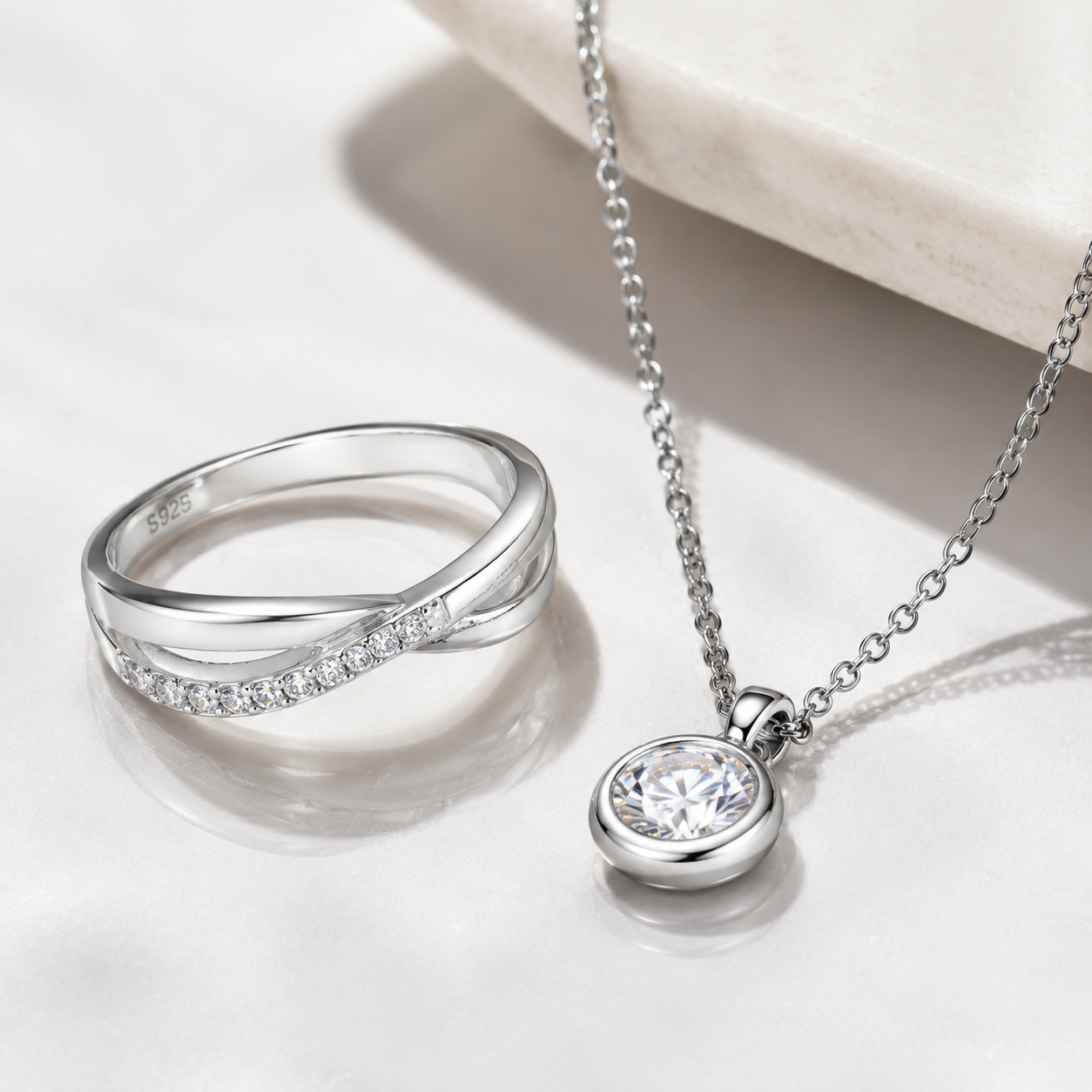 premium studio shot of a complete stainless steel necklace with a sterling-silver pendant on a brushed metal surface, showing connection detail and clasp in a well-lit, uncluttered setup